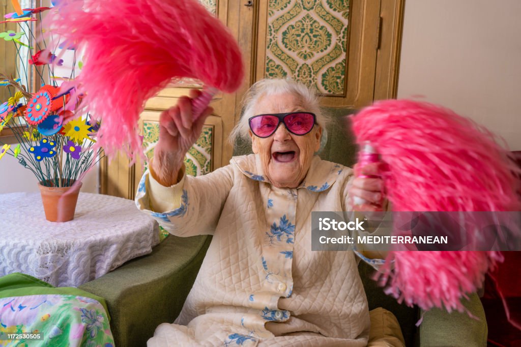 Cheerleader pom-pom elderly woman happy Cheerleader pom-pom elderly woman happy at living room Senior Adult Stock Photo