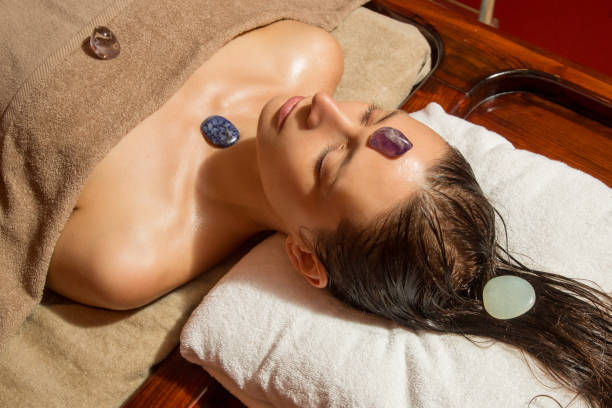 woman in the spa having energizing crystal massage - reiki alternative medicine chakra recovery imagens e fotografias de stock