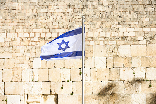 Vista de cerca de la bandera israelí ondeando frente al Muro de las Lamentaciones (Muro de las Lamentaciones) en Jerusalén, Israel. La Bandera de Israel se puede ver en todo el país, y es un símbolo de alegría y sueños. photo