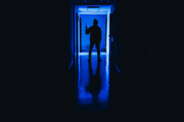 murder, kill and people concept - Criminal or murderer wearing a mask in silhouette holding knife inside a condo at crime scene