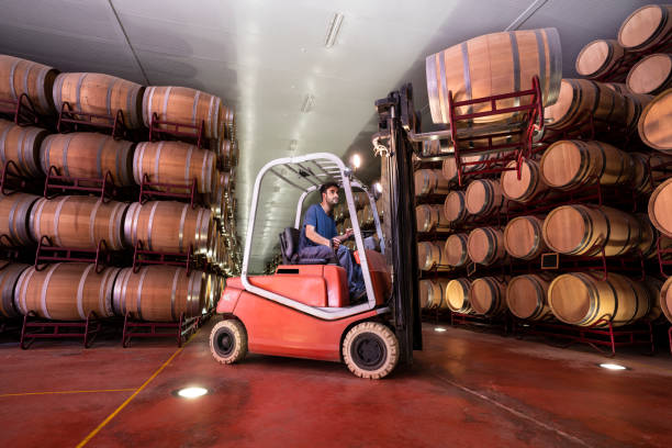 Barrel winery pallet truck jack forklift Oak Barrel winery pallet truck jack forklift young beard worker man in cellar wine shipping stock pictures, royalty-free photos & images