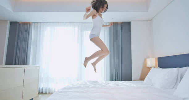 istock Young woman jump on bed 1172536995