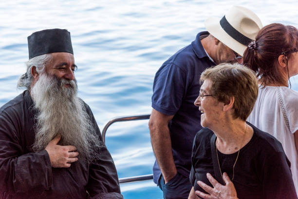 personnes priant et faisant des souhaits avec le prêtre du monastère par bateau d'excursion dans la république monastique de mt athos, grèce - greek bible photos et images de collection