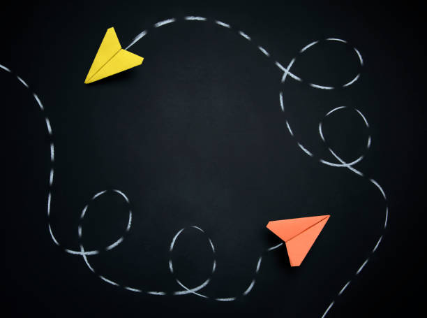 istock Two Paper Airplanes with Dotted Chalk Path Creative Idea on Black Chalkboard 1172544956