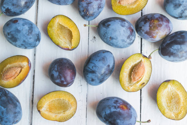 istock Fresh and ripped delicious plums on old white wooden table. High angle view 1172548720