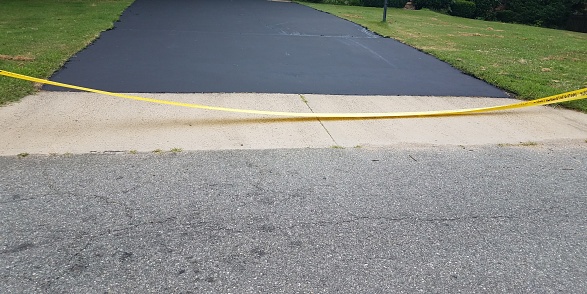 istock new asphalt driveway and yellow caution tape 1172553927