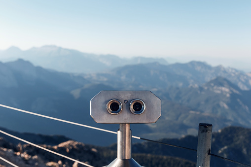 Stationary binoculars or binoscope on the viewing platform against the background beautiful landscape in the mountains. Lovely view of the Taurus Mountains and the Mediterranean coast. Kemer, Turkey