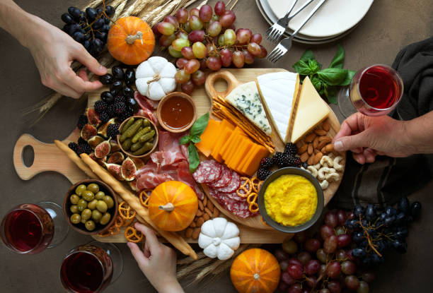 Fall party charcuterie board, view from above Fall holidays party table with friends hands picking some fingerfoods from charcuterie board, top down view prosciutto brie stock pictures, royalty-free photos & images