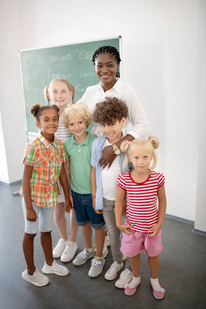 istock Loving smiling teacher hugging her cute smart pupils 1172559686