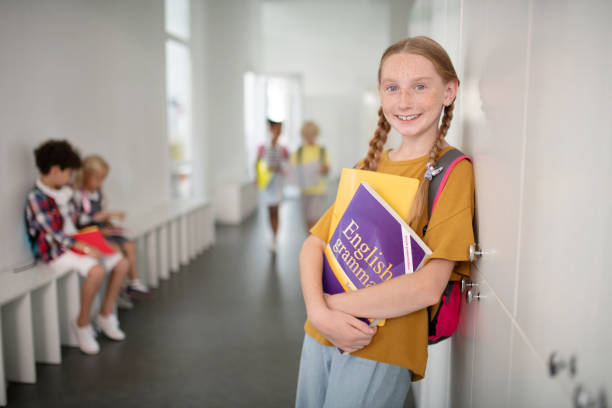 istock Beautiful schoolgirl holding boy while standing near locker 1172559992