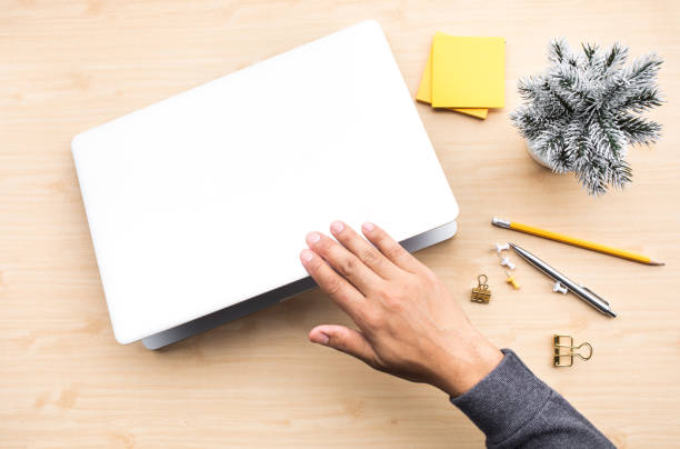 Young man closing computer laptop with accessories object on wood desk table