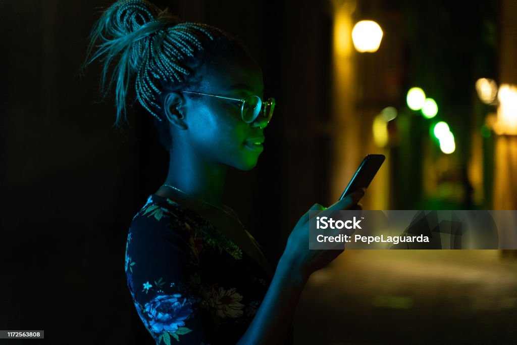 Woman sending a text message with her smartphone at night Cool young woman sending a text message with her smartphone at night Street Light Stock Photo