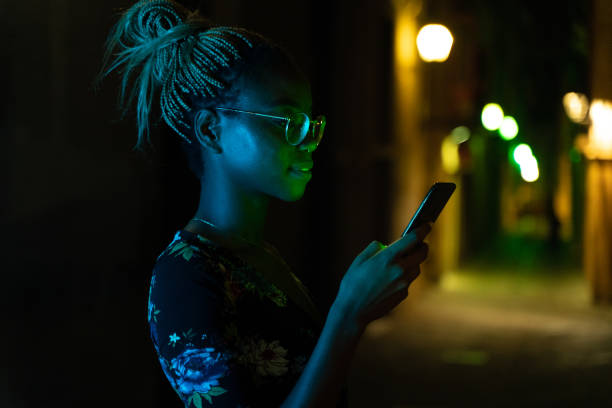 Woman sending a text message with her smartphone at night Cool young woman sending a text message with her smartphone at night mobile phone lights up stock pictures, royalty-free photos & images