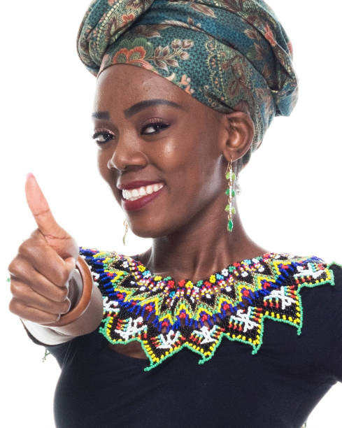Headshot / profile view of 20-29 years old african ethnicity / african-american ethnicity young women / female in front of white background wearing headscarf / dress / traditional clothing who is cheerful / happy and showing thumbs up / ok sign headshot / vista de perfil de 20-29 años de edad etnia africana / etnia afroamericana mujeres jóvenes / mujer delante de fondo blanco usando pañuelo / vestido / ropa tradicional que es alegre / feliz y mostrando pulgares hacia arriba / ok signo