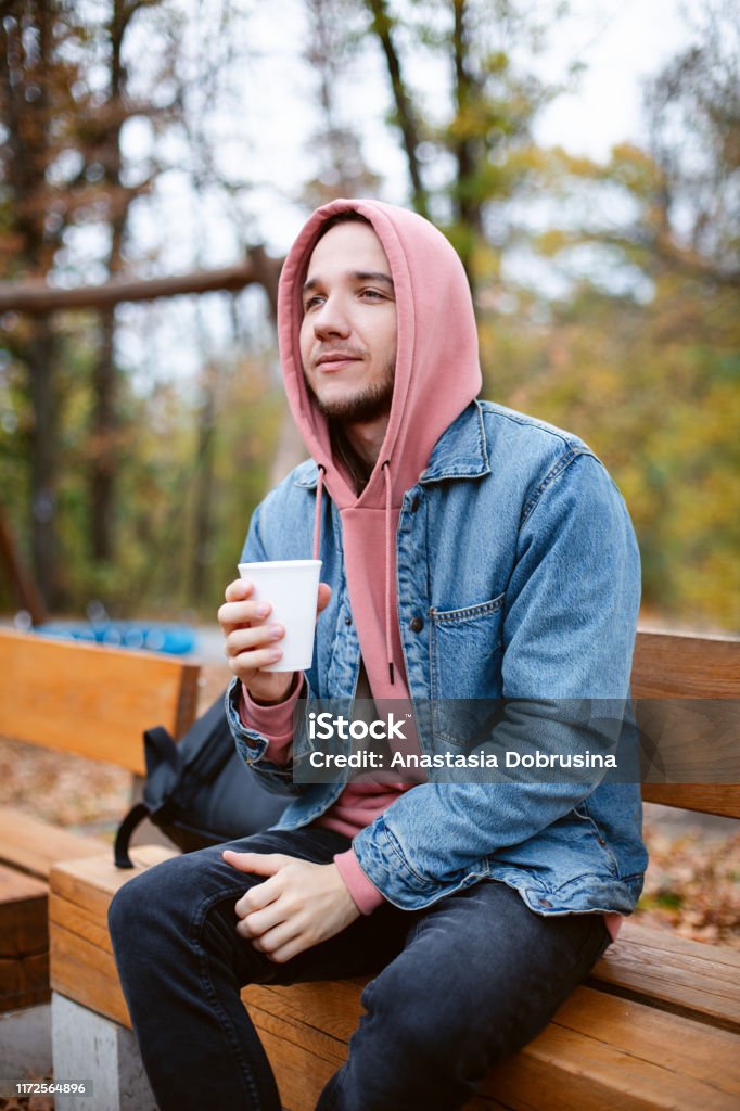Man With Beard In Fashion Pink Hoodie And Denim Jacket Sitting Outside And  Drinking Coffee Or Hot Tea Stock Photo - Download Image Now - iStock