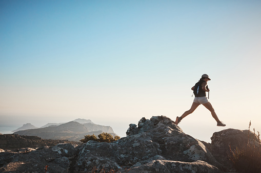 Shot of a young woman hiking up a mountain