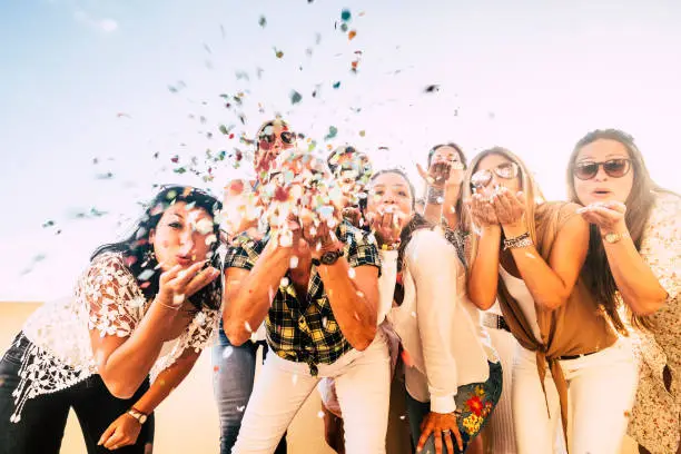 Photo of Happiness and joyful concept - group of happy women people celebrate. all together blowing confetti and having fun - new year eve and party event for group of beautiful girls -white clear  background