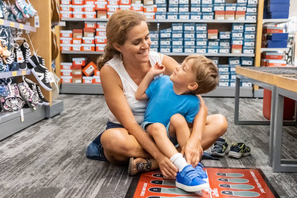 彼女の息子のための靴のための成熟した女性の買い物 - shoe store shoe shopping retail ストックフォトと画像