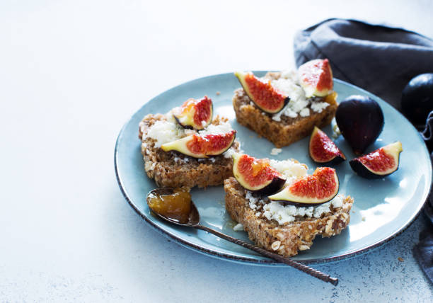 Open sandwiches with soft cheese and figs on a blue plate stock photo