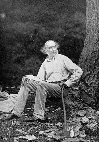 Portrait of William Ewart Gladstone (1809 - 1898) while cutting trees at Hawarden, Wales. Vintage photo etching circa late 19th century.