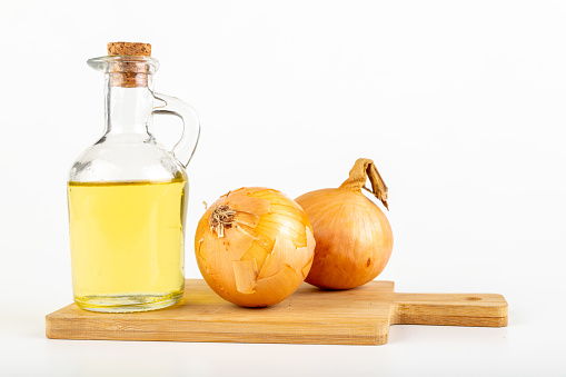 Home remedy for colds from onions. Squeezed vegetable juice in a bottle. Light background.