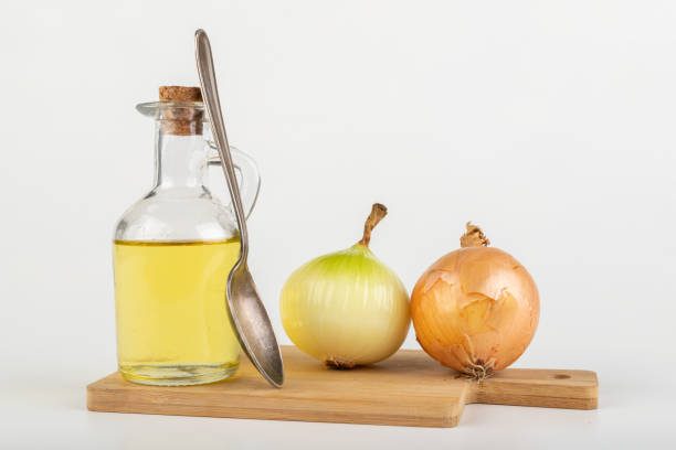 Home remedy for colds from onions. Squeezed vegetable juice in a bottle. Light background.
