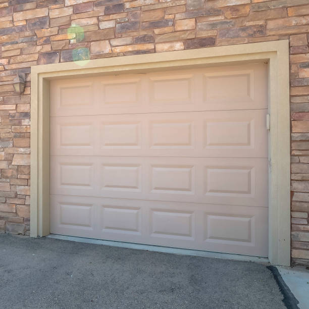 istock Square White garage doors of a home against exterior wall covered with stone bricks 1172582035