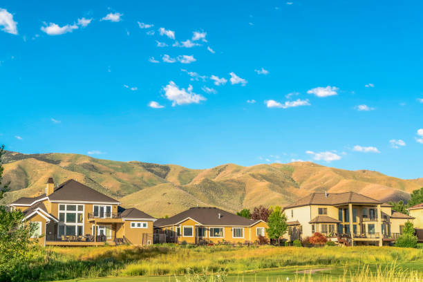 istock Homes in the middle of a grass covered terrain and distant towering mountain 1172583274