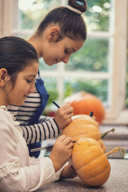 istock Two young girls making Jack-o-Lantern from pumpkins, they preparing for Halloween celebration 1172584729