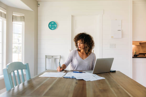 mujer haciendo finanzas en casa - making fotografías e imágenes de stock