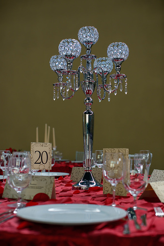 Formal table setting for a wedding or a special event featuring a timeless five bobeche crystal candelabra centerpiece, white china, invitation cards, glassware and silverware in the order of use.