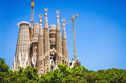 Barcelona, Catalonia, Spain - September 16th, 2013: Sagrada Familia Cathedral designed by famous architect Gaudi under blue summer sky with construction cranes, building up the cathedral towers. Catalonia, Barcelona, Spain, Europe