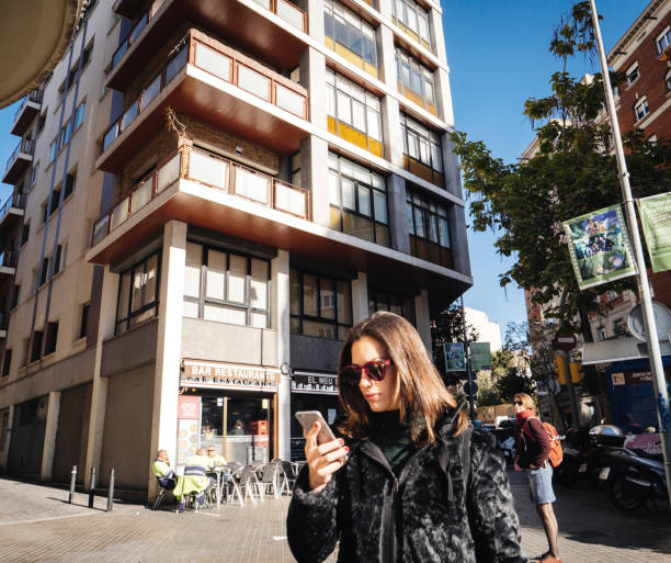 joven caminando por la calle barcelona usando el teléfono - candid downtown district editorial horizontal fotografías e imágenes de stock