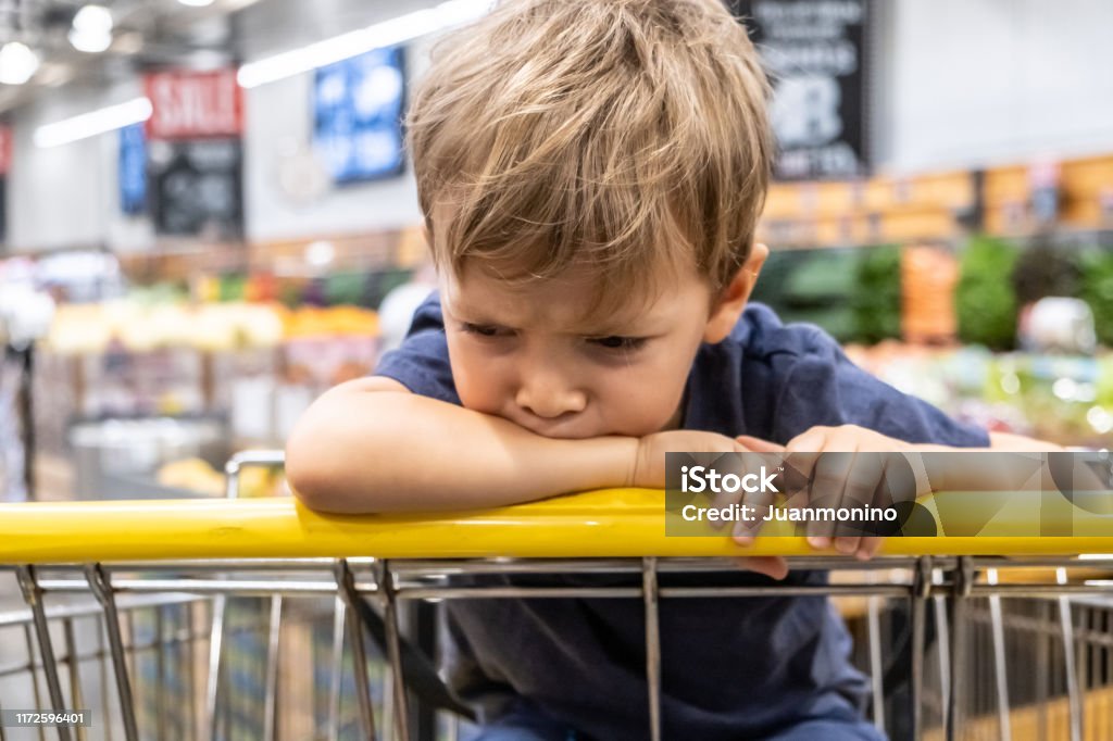 Nahaufnahme frustriert Kind Junge schaut weg sitzend in einem Einkaufswagen - Lizenzfrei Kind Stock-Foto