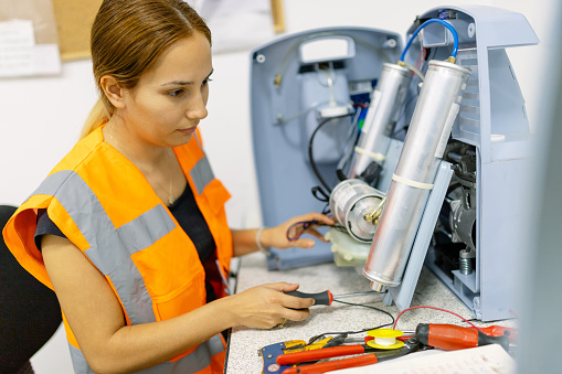 Female technician repairing product and using screwdriver
