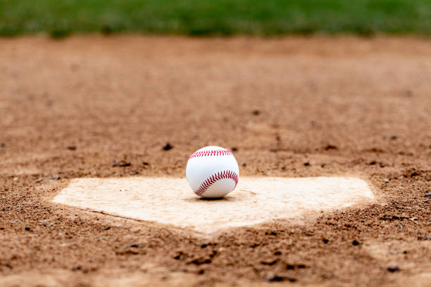 Home Plate Baseball Baseball laying on a worn home plate or base home plate stock pictures, royalty-free photos & images