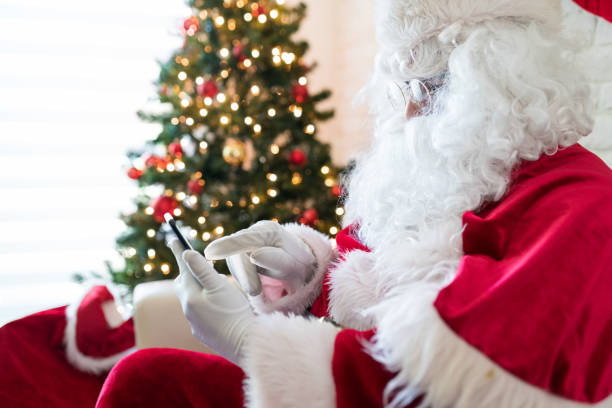 istock Man in Santa costume using smart phone at home 1172608942