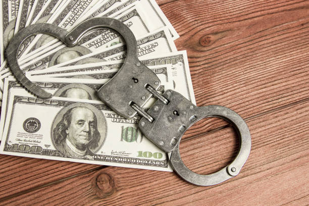 istock dollars money and handcuffs on wood texture background. 1172609728