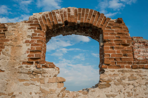 Window arch of an old abandoned building, against a sky with clouds