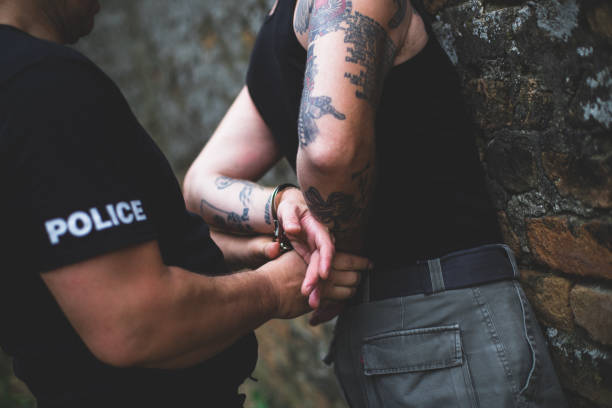 Under arrest A policeman putting handcuffs on a gang banger. drug addiction tattoos stock pictures, royalty-free photos & images