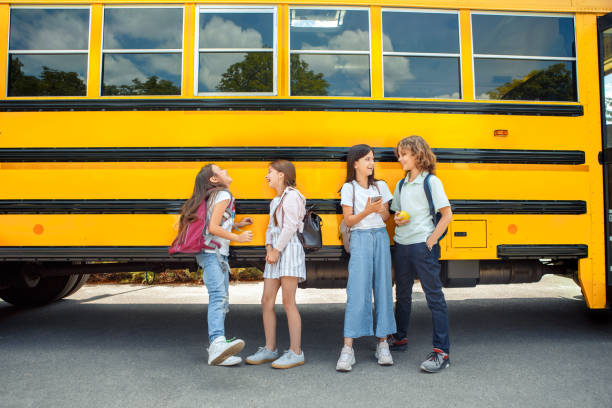 istock Classmates going to school by bus standing talking eating apple browsing smartphone laughing happy 1172612448