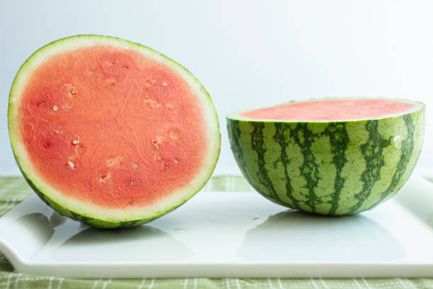 wassermelone halbiert auf einer tischplatte - gezweitelt stock-fotos und bilder