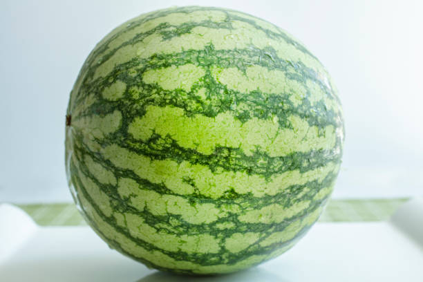 Whold watermelon on a white ceramic tray and table top with a green tablecloth and white background