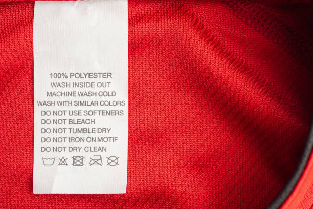 White laundry care washing instructions clothes label on red jersey polyester sport shirt White laundry care washing instructions clothes label on red jersey polyester sport shirt polyester photos stock pictures, royalty-free photos & images