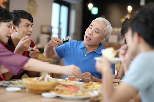 Happy extended family communicating while having a lunch at dining table