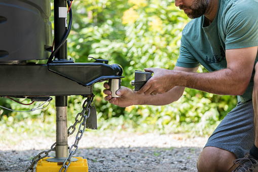 A man is Installing the camper trailer padlock during camping in summer.