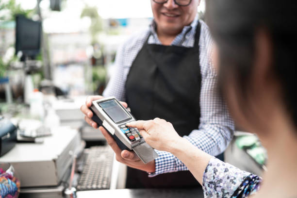 klient umieszczając hasło przy płatności kartą kredytową przy kasie w małej firmie - cash register paying checkout counter cashier zdjęcia i obrazy z banku zdjęć