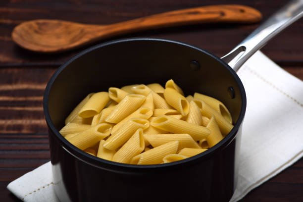 Cooked noodles (Penne Rigate) inside an professional anodized nonstick aluminum pan. stock photo