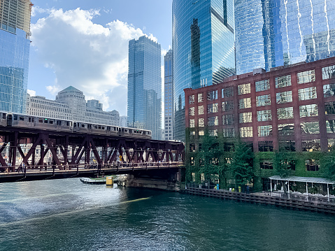 View of elevated train track with el train crossing Lake Street and the Chicago River in summer