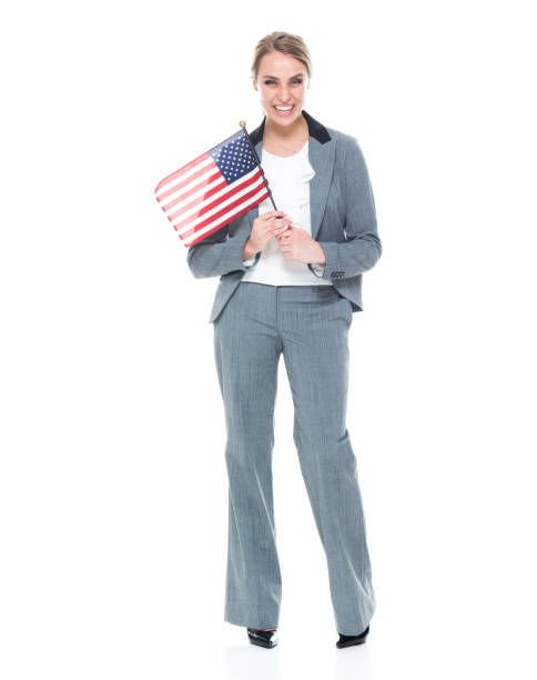 full length / front view of 20-29 years old adult beautiful caucasian female / young women businesswoman / business person standing in front of white background wearing a suit who is smiling / happy / cheerful and showing patriotism - one young woman only only young women one woman only 20 25 years imagens e fotografias de stock